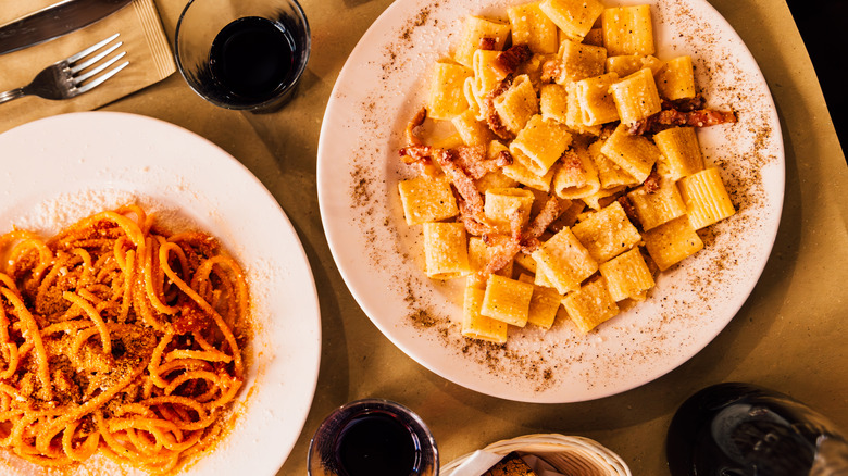 Overhead view of plates of pasta and glasses of red wine on a restaurant table