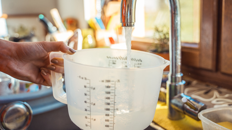 filling up a measuring cup with hot water