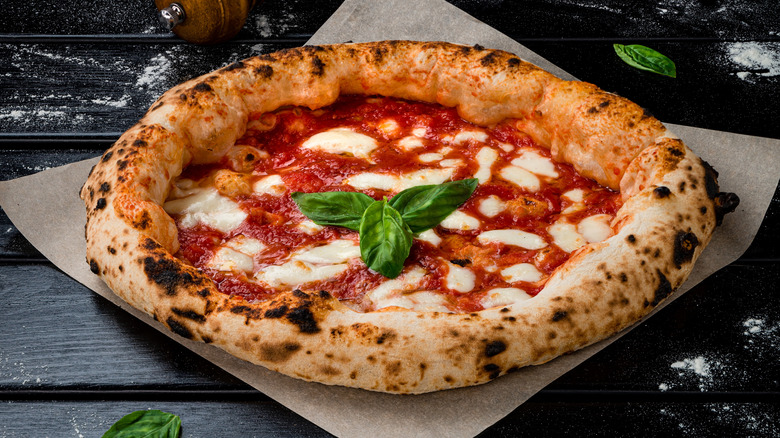 wood-fired margherita pizza topped with three basil leaves