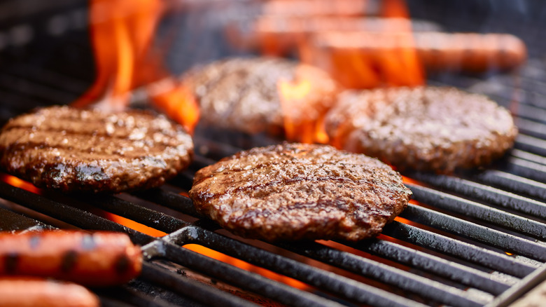 Hamburgers and hot dogs on a flaming grill