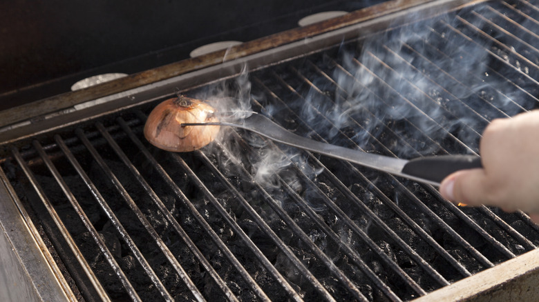 Fork rubbing an onion on a hot grill