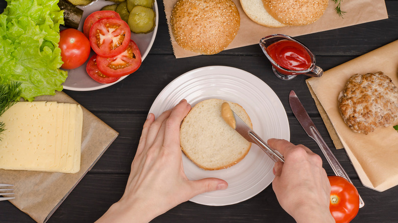 Person spreads sauce on burger bun