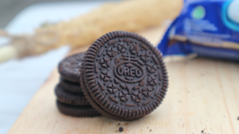 Three Oreo cookies stacked on a cutting board