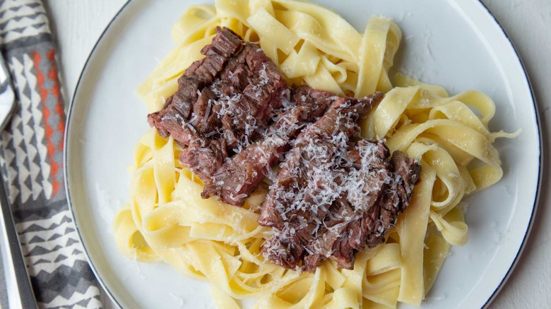 Alfredo pasta with sliced steak and Parmesan