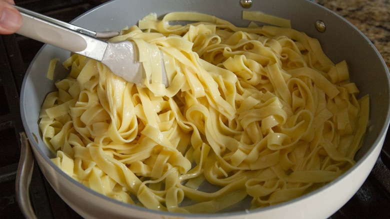 Tossing pasta with creamy parmesan