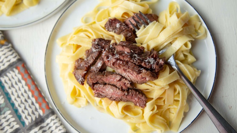 Steak Alfredo pasta on plate with fork