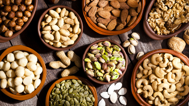 bowls of various kinds of nuts on wood surface