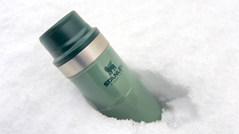 green Stanley Action Trigger thermos mug in the snow