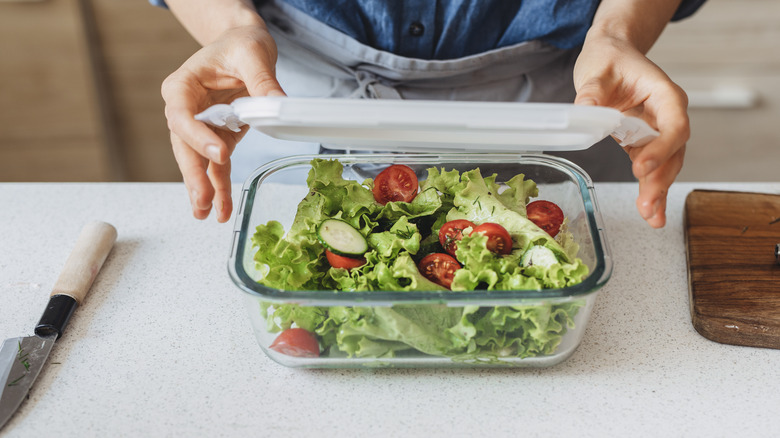 Person putting salad in container