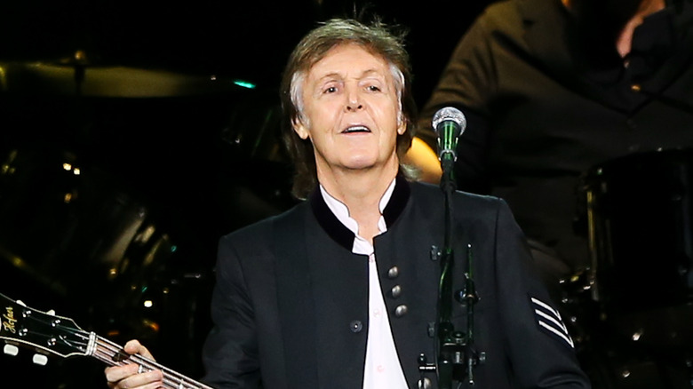 Paul McCartney playing bass on a stage.