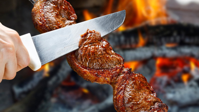 Slicing pincanha from a skewer at a Brazilian steakhouse