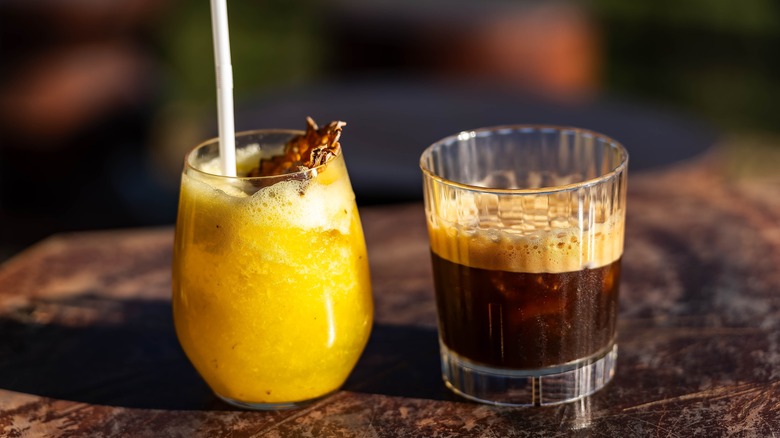 A glass of pineapple juice and an iced coffee