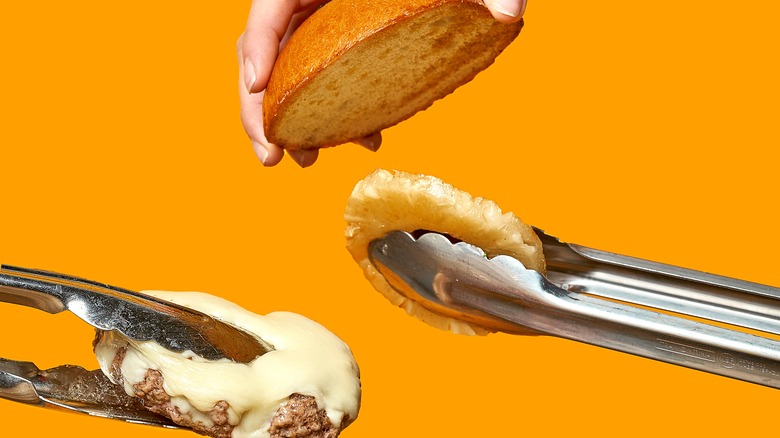 Tongs holding a bun, burger, and pineapple 