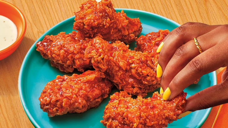 Person grabbing wings from blue plate