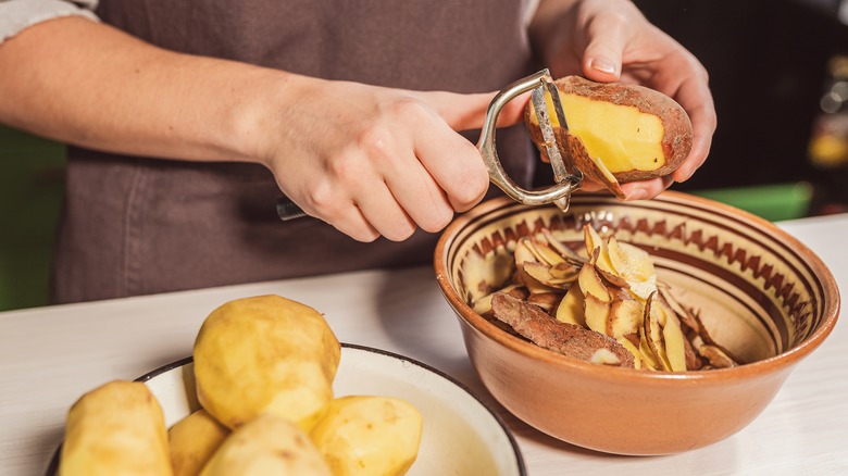 potatoes being peeled into a bowl