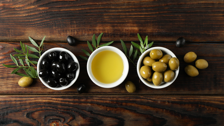 Olives and oil in bowls on wood