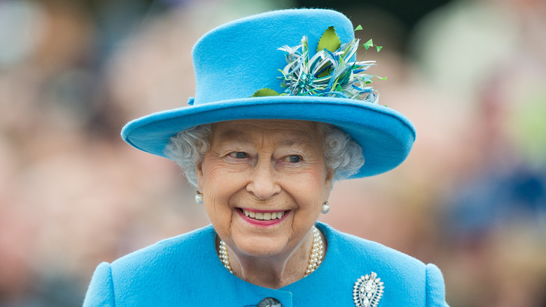 Queen Elizabeth II in a blue outfit, smiling