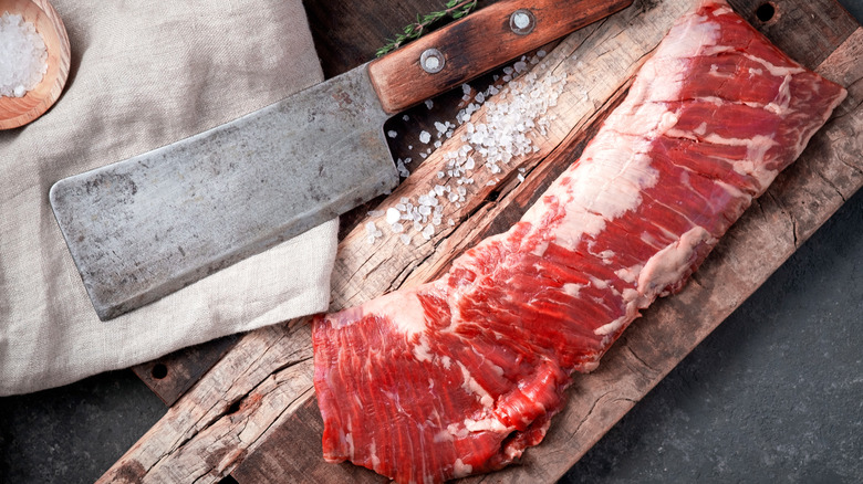 Raw skirt steak with cleaver