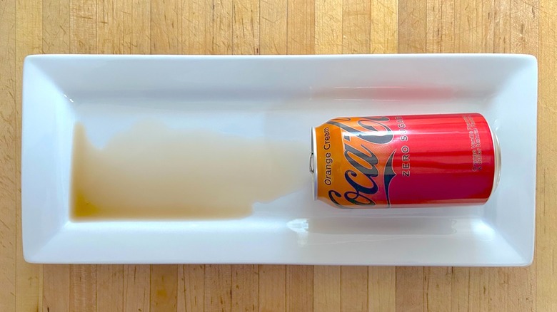 Spilled can of Coca-Cola Orange Cream on white rectangular plate