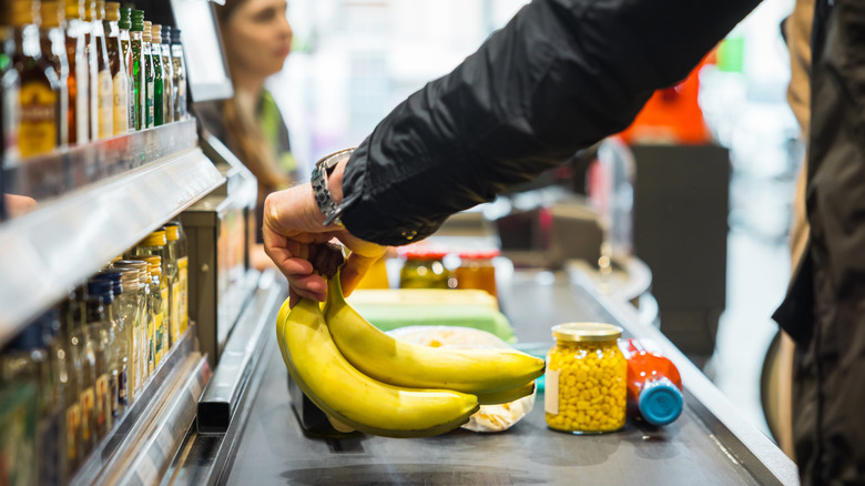 Person places groceries on conveyor belt