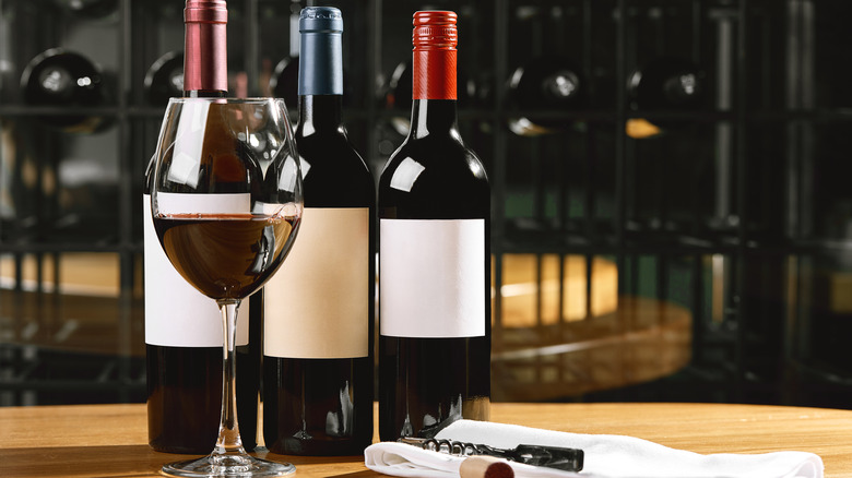 Three bottles of wine and a glass of red wine
