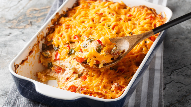Chicken tortilla casserole in baking dish with wooden spoon