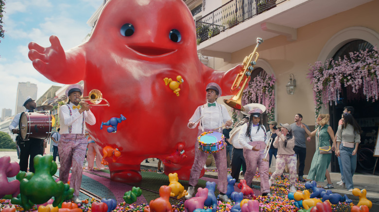 Big gummy character covered in Nerds with marching band