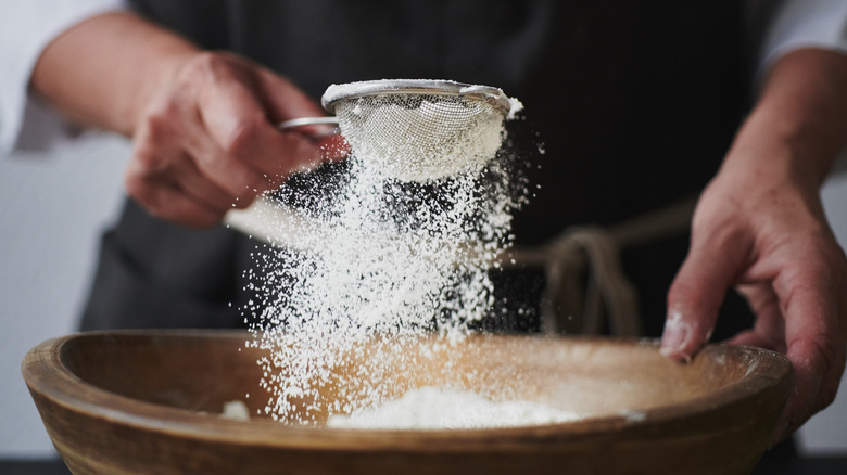 Hand sifting flour into bowl