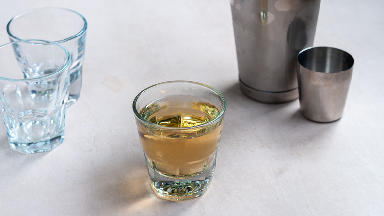 filled shot glass alongside barware