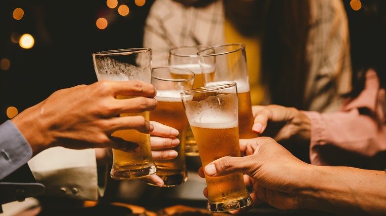 Group clinks glasses of beer at bar