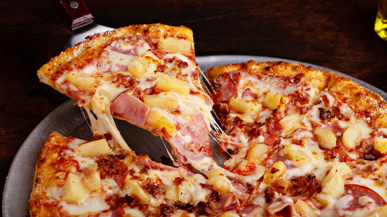 a triangle cut pizza slice being taken from pie