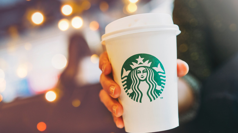 holding cup of Starbucks coffee
