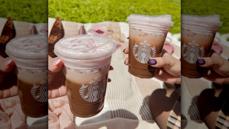 Hands holding iced mocha with cherry cold foam
