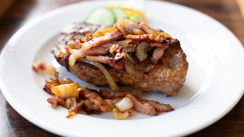 Grilled steak topped with bacon and caramelized onions