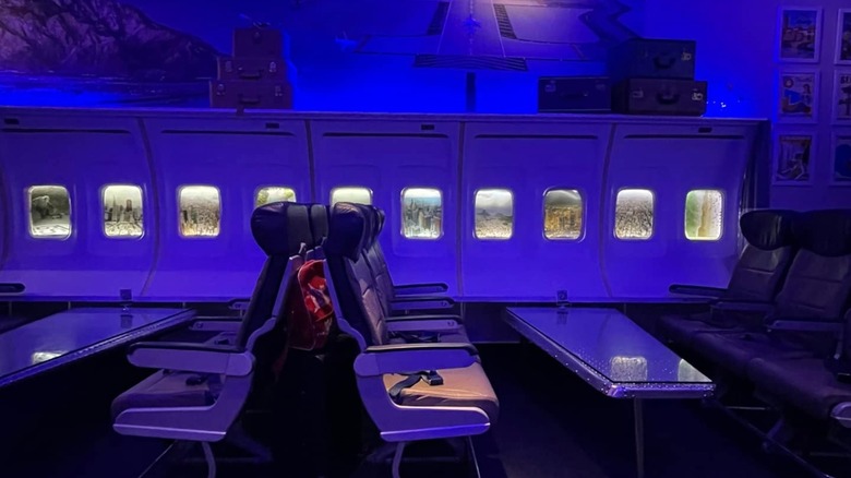 Interior of PS Air Bar with seats and tables in front of aircraft windows