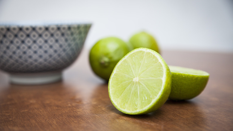 four limes in a yellow bowl