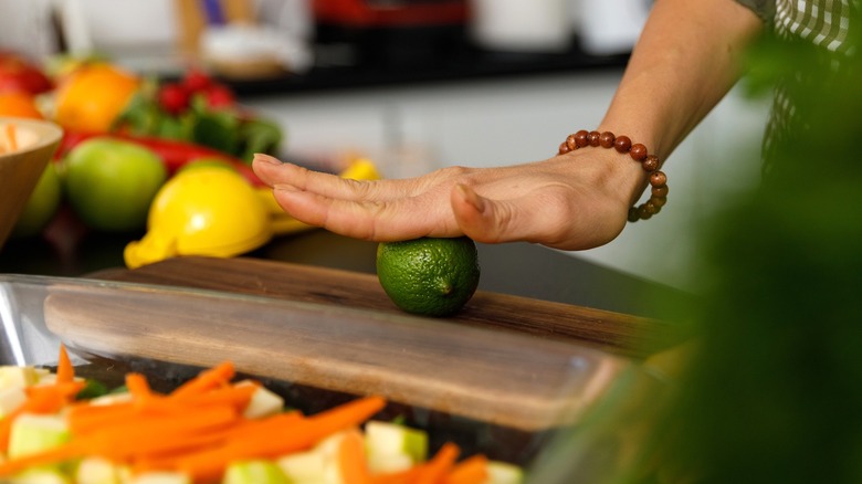 hand rolling a lime on a cutting board