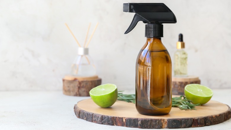 spray bottle next to cut lime, rosemary, incense, and oil