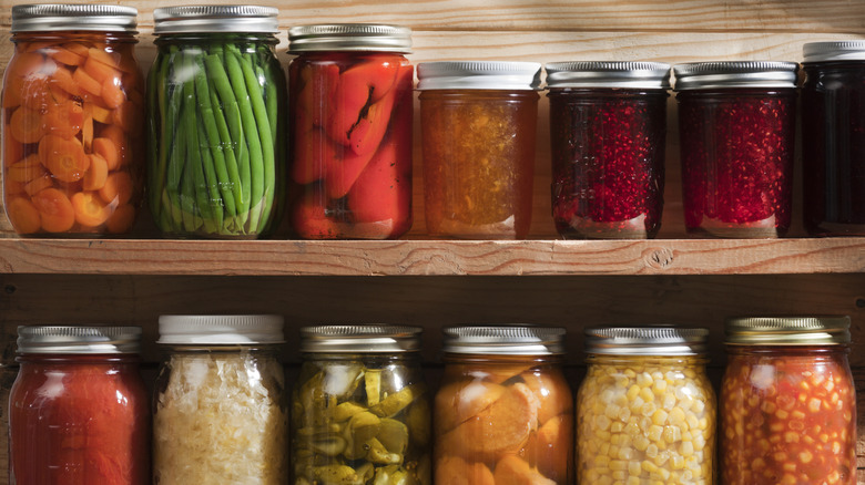 mason jars with canned and pickled foods lined up on shelf