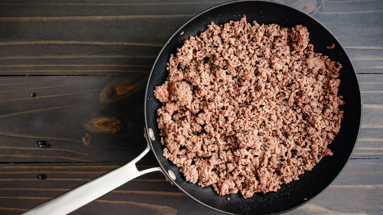 Ground beef in pan on wooden table