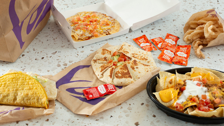 A spread of several Taco Bell menu items and hot sauces