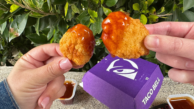 Hands hold chicken nuggets dipped in Diablo Sauce