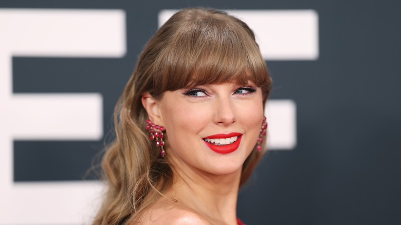 Taylor Swift at the Grammy Awards, smiling over her right shoulder with red earrings
