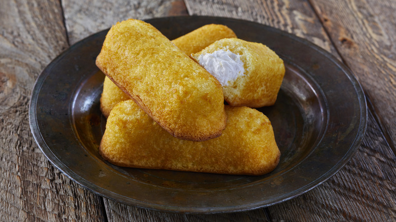 A plate of twinkies with one broken open to show the cream filling