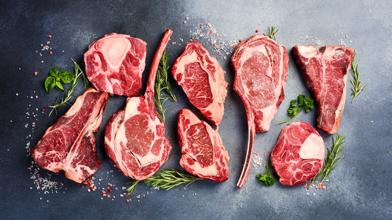 Several different cuts of raw steak arranged on a granite background