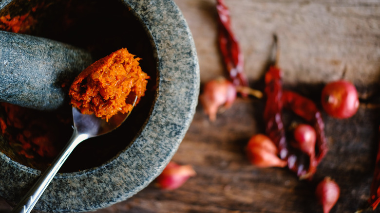 a mortal and pestle with red curry paste