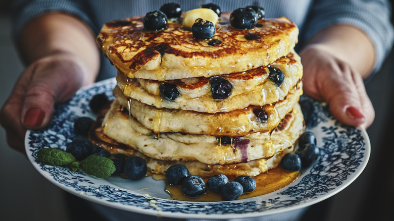 Person holding plate of pancakes