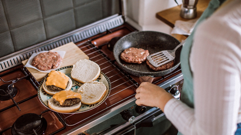 woman cooking burger on stove