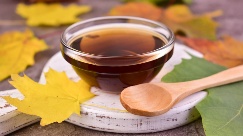 Maple syrup in a bowl next to a wooden spoon