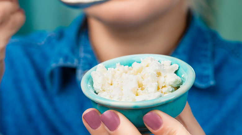 A woman holds a small bowl of cottage cheese